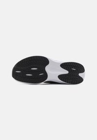 Schwarz-weißer Sneaker-Sohlen mit strukturiertem Gummi, der ein komplexes Profilmuster und ein auffälliges Markenlogo in der Nähe der Ferse aufweist.