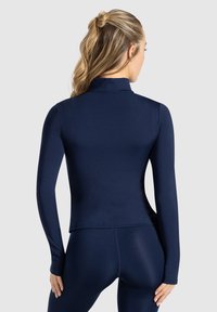 Marineblå långärmad prestandatröja med hög krage, slät textur och åtsittande design. Lämplig för aktiv träning.