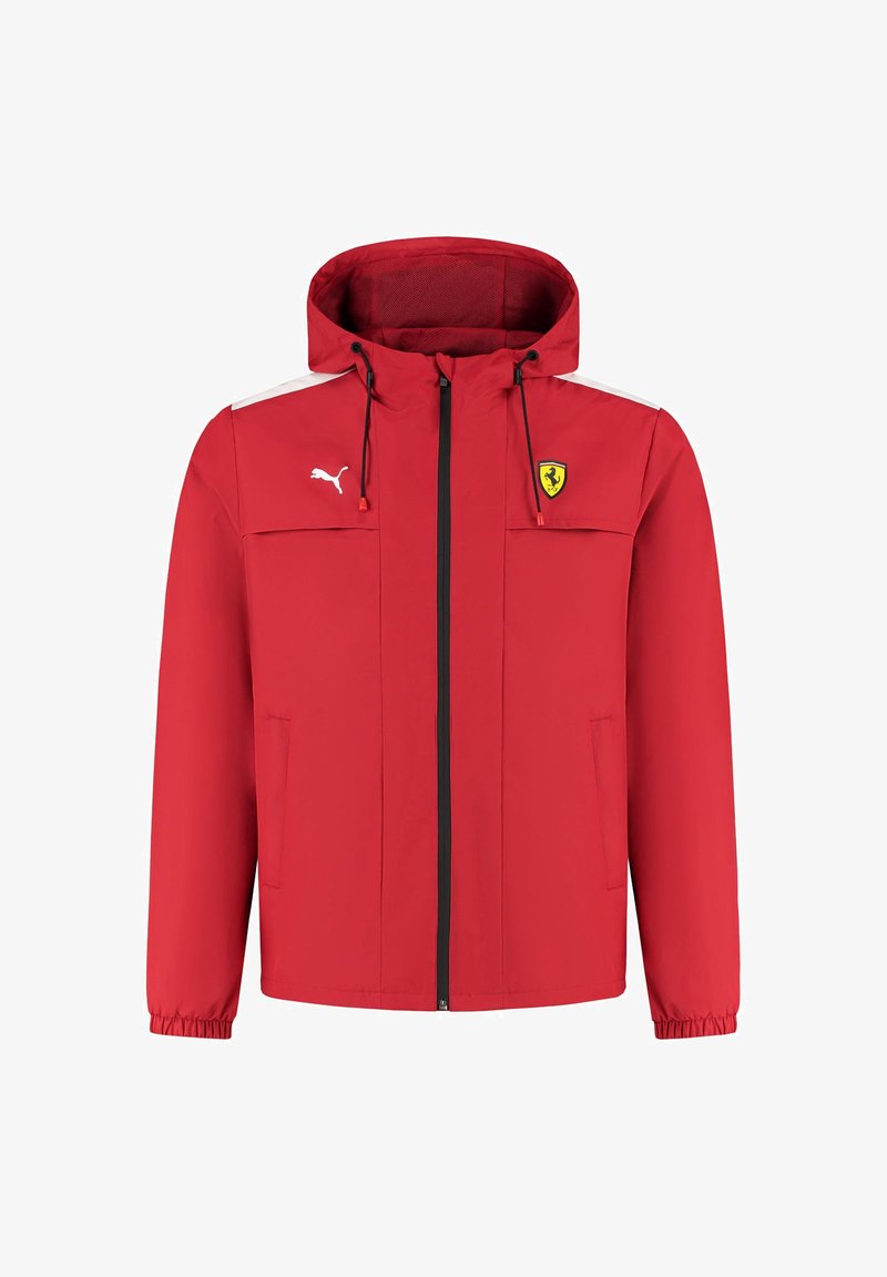 Czerwona kurtka przeciwdeszczowa z kapturem. Posiada białe akcenty, zamek błyskawiczny, kieszenie boczne oraz logo Ferrari na piersi. Wykonana z lekkiego materiału.