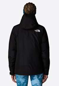 Czarna wodoodporna kurtka z kapturem, z logo na górnej części pleców oraz z wyraźną strukturą. Dolny brzeg ma prosty krój.