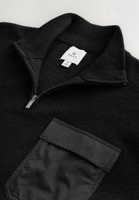 Crni pulover s patentom na ovratniku, izrađen od teksturiranog pletenog materijala i s prednjim džepom od glatkog materijala. Na etiketi su vidljivi brend i veličina.