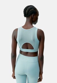 Lichtblauwe sportbeha met een mesh achterkant, ronde uitsparing en brede banden, gecombineerd met bijpassende high-waisted leggings, gemaakt van rekbaar materiaal.