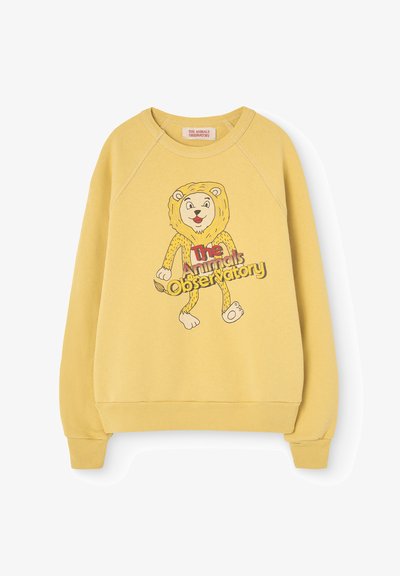 Geel sweatshirt met raglanmouwen heeft een cartoonleeuw-graphic en de tekst "The Animals Observatory" in een speelse lettertype aan de voorkant.