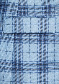 Jasnoniebieska tkanina w kratkę z różnymi odcieniami niebieskiego i czarnego. Charakteryzuje się teksturowanym splotem oraz kieszenią na górze po lewej stronie.