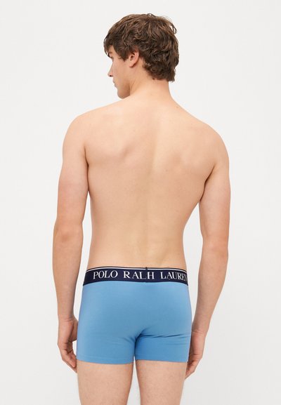 Boxeri din bumbac albastru cu un elastic în nuanța marinei, pe care scrie "POLO RALPH LAUREN" cu litere albe, văzuți din spate.