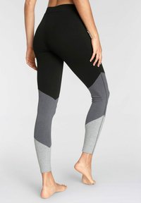 Svarta och grå leggings med färgblockdesign och figurnära passform, tillverkade i stretchigt tyg med en slät, matt yta.