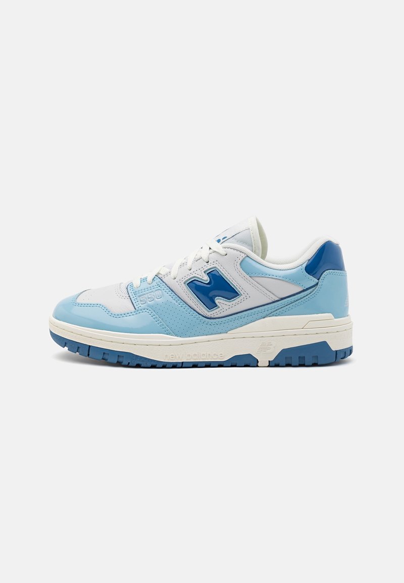 Baskets basses avec des panneaux blancs, bleu clair et bleu foncé, une semelle blanche épaisse et un grand logo bleu "N" sur le côté.