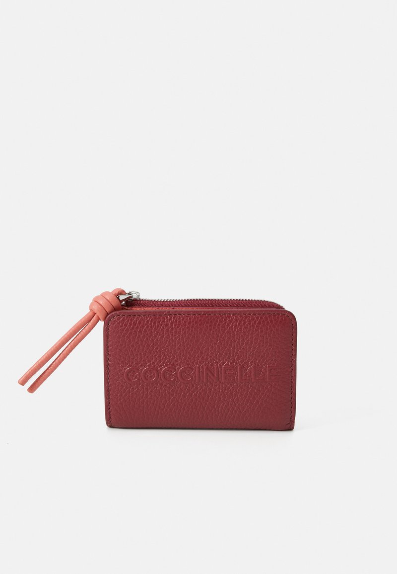 Portafoglio in pelle rossa con texture, chiusura a zip e un tirante in pelle rosa. Presenta il nome del marchio in rilievo sulla parte anteriore e un design compatto.