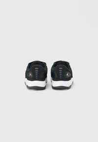 Ζευγάρι ασπρόμαυρα αθλητικά παπούτσια εμφανιζόμενα από πίσω με λογότυπο στη φτέρνα και γκρι οβάλ λεπτομέρειες πάνω από τη σόλα.