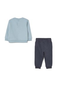 Hellblaues Sweatshirt mit langen Ärmeln und einem Knopfdetail im Rücken, kombiniert mit dunkeln marineblauen Sweatpants mit elastischem Bund und gerippten Bündchen.