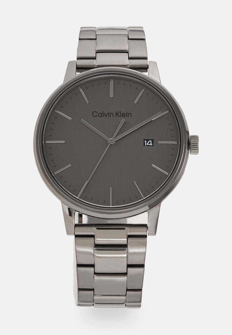 Calvin Klein Uhr mit einem grauen Metallgehäuse und Zifferblatt, minimalistischen Stundenmarkierungen und einem Armband aus stainless Steel in Silber. Datumsanzeige auf der 3-Uhr-Position.