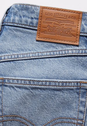 Jasnoniebieskie jeansy jeansowe z tylną kieszenią z widoczną brązową skórzaną etykietą marki Levi Strauss & Co. przyszytą nad kieszenią.