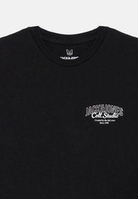 Μαύρο βαμβακερό μπλουζάκι με κανονικό λαιμό και κοντά μανίκια. Διαθέτει �λευκό λογότυπο στην αριστερή πλευρά του στήθους, καθαρή σχεδίαση και μαλακή υφή.