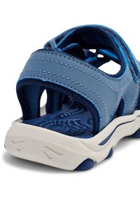 Blå sandaler med övre del i mjukt läder, kontrasterande blå sömmar, justerbara remmar och en texturerad vit gummisula för grepp.