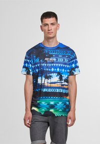 Short-sleeve graphic t-shirt featuring a blue and turquoise design with palm trees and zigzag patterns, made from lightweight material.
