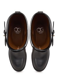 Botine negre din piele cu o textură netedă, având vârful rotunjit și o curea decorativă pe partea laterală. Interiorul prezintă logo-ul mărcii.
