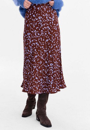 Brązowa kwiatowa spódnica midi o zwiewnym kroju z jasnoniebieskimi wzorami. Wykonana z lekkiego materiału, zakończona delikatnie rozszerzanym dołem. Widoczne brązowe buty.