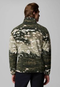 Giacca in pile con collo alto, caratterizzata da un motivo camouflage verde e beige, superficie texturizzata e rifiniture nere lungo l'orlo e le maniche.