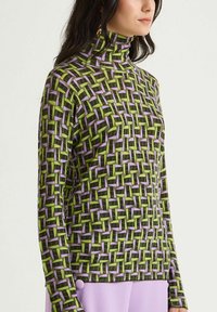 Maglione a collo alto finto con motivo geometrico in verde, viola e nero. Texture a coste con maniche lunghe e design aderente.