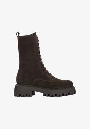 Brown suede lace-up ankle boots with a chunky black rubber sole and textured surface. Features a pull tab at the heel and dark laces.