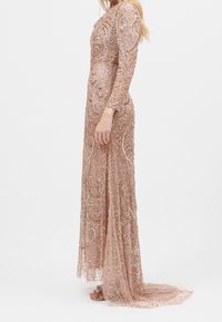 Perlebesat langærmet kjole i blød rosenfarve, med indviklede svulmønstre og en flydende nederdel med tog. Semi-gennemsigtigt stof og detaljerede udsmykninger.