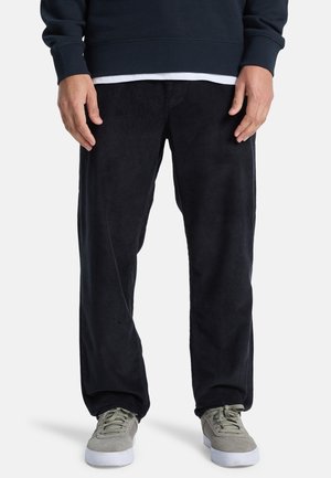 Zwarte corduroy broek met een relaxed fit, met verticale ribbels en een gladde textuur, gecombineerd met grijze lage sneakers.