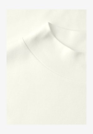 Gros plan sur un tissu blanc avec un col haut et doux, montrant une texture lisse et des détails de couture raffinés.