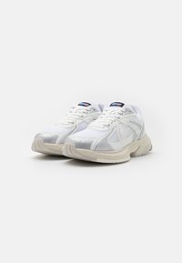 Weiße sportliche Sneaker mit Netz- und Synthetiküberzügen, ausgestattet mit einer runden Zehe, einer gepolsterten Sohle und dezenten grauen Akzenten.