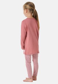 Lange mouwen, roze katoenen top gecombineerd met gestreepte roze en witte leggings. De outfit heeft een ontspannen pasvorm en een zachte textuur.