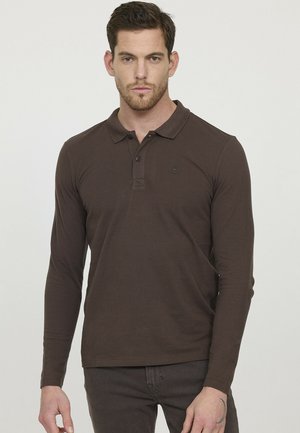 Polo à manches longues de couleur marron avec un col, une patte de boutonnage à trois boutons et un petit logo sur le côté gauche. Le tissu est lisse et extensible.