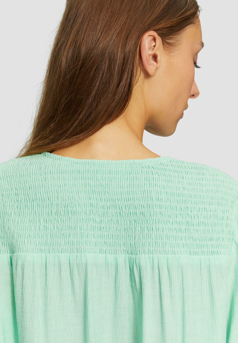 Mintgrünes Blusenshirt mit strukturierten Rüschen an den Schultern und am Rücken, mit lockerem Schnitt und weichem, leichtem Material.