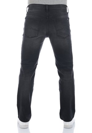 Czarne dżinsy o prostym kroju nogawki, z dwoma tylnymi kieszeniami oraz widoczną metką marki przy pasku. Gładka tekstura.