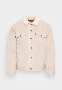 Beige kordjacka med fårskinnskrage, framknäppning med knappar och två bröstfickor. Har en lätt textur och slitstarkt tyg.