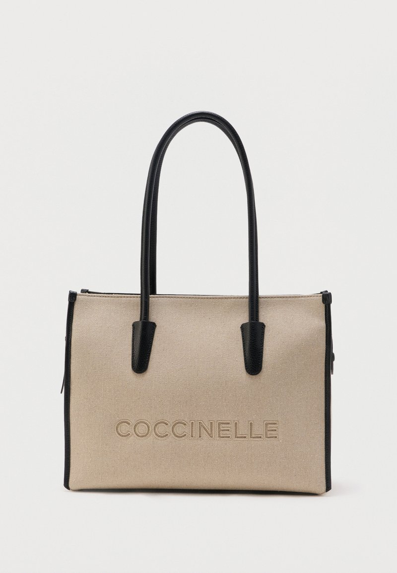 Μπεζ ορθογώνια τσάντα tote με μαύρες χειρολαβές και διακοσμητικά, με ανάγλυφο λογότυπο "COCCINELLE" στο μπροστινό μέρος.