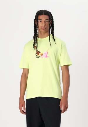 T-shirt en coton vert néon avec un graphisme d'un oiseau et d'un popsicle rose sur le devant. Manches courtes, coupe décontractée.
