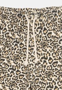 Šorts s leopard uzorkom s pojasom na vezanje, izrađeni od mekanog materijala, s crnim i smeškim mrljama na bež pozadini.