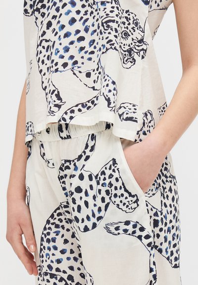 Leopard print top and pants set in a cream fabric. Features black and blue spots, relaxed fit, and pockets on the pants.