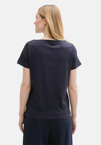 Camiseta de manga corta navy con un corte relajado, cuello redondo y tejido de algodón suave. Presenta un sutil detalle de costura en la parte posterior.