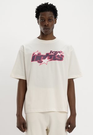 Weißes Baumwoll-T-Shirt mit einem mutigen grafischen Druck in Pink und Schwarz, verziert mit Sternen. Kurze Ärmel und eine lockere Passform prägen das Design.