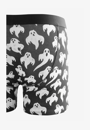 Černé boxerky s bílými vzory duchů, s černým pasem a hladkým povrchem. Podrobnosti o šití jsou patrné podél švů.