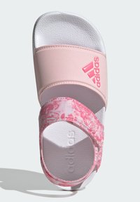 Chancla Adidas con una correa rosa clara, patrón veteado en tonos de rosa y plantilla texturizada blanca. Presenta el logo de Adidas en la correa superior.