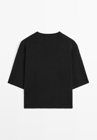 Black knit top with a crew neck, short raglan sleeves, and a loose fit. The fabric appears soft with a smooth texture and minimal detailing.