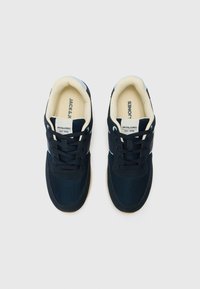 Sapatilhas azul-marinho com parte superior em malha e tecido, forro creme e detalhes brancos. Apresenta um design clássico com atacadores e colarinho almofadado.