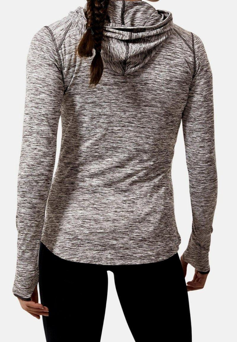 Femme avec une longue tresse portant un haut gris texturé à capuche et manches longues, ainsi que des leggings noirs, vue de dos.