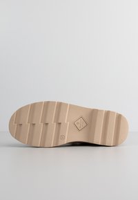 Shoe sole with a textured, beige rubber material featuring tread patterns and a diamond logo, labels "GANT" and size "37" embossed.