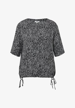 Czarny i biały top w wzory z krótkimi rękawami, okrągłym dekoltem i regulowanymi bocznymi związaniami. Posiada geometryczny nadruk i luźny krój.