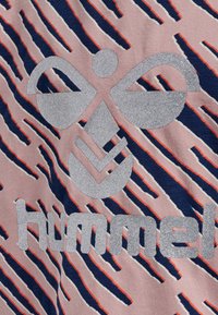 Rosa tyg med marinblå och orange diagonala ränder har en stor, glittrig silverlogga och texten "hummel" i botten.