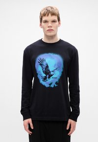 Tricou negru cu mânecă lungă, prezentând o grafică albastră cu un vultur și textul "HUGO." Material moale și croială relaxată, cu decolteu rotund.