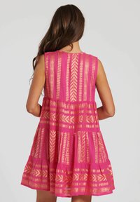 Rosa ärmlös klänning med guldmönstrade detaljer, med en tierad design och lättviktig tyg, som visar en dekorativ rygg.