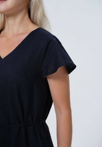 Mörkblå klänning i lätt tyg, med korta volangärmar och V-ringning, samt midja med bälte.